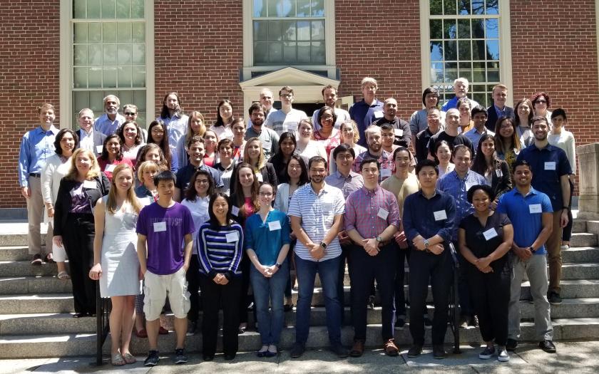 Students and Faculty take a group photo in front of a Brown building