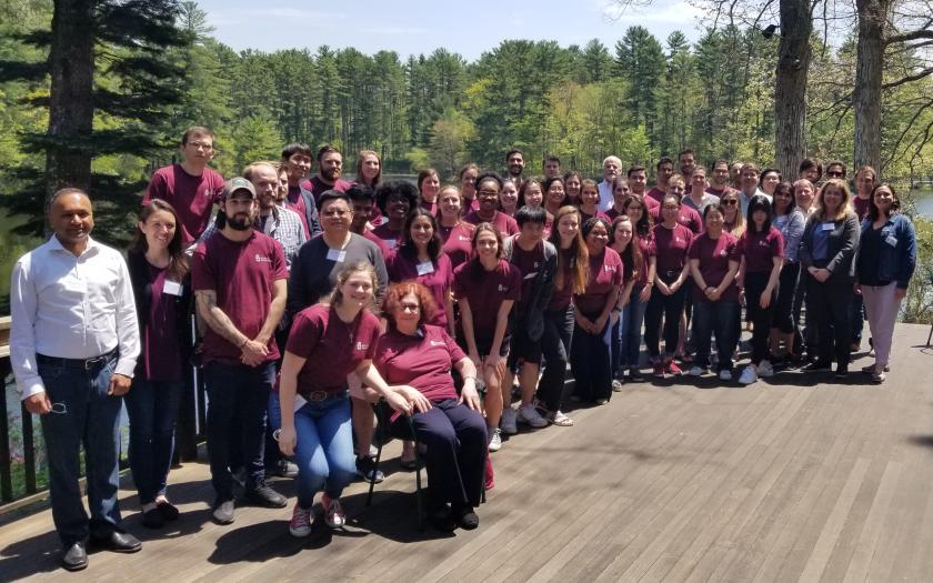 Group of faculty staff and students, mostly wearing a group tshirt