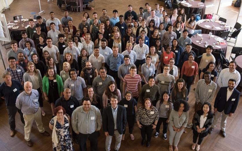 Students and faculty pose for a group photo, looking up