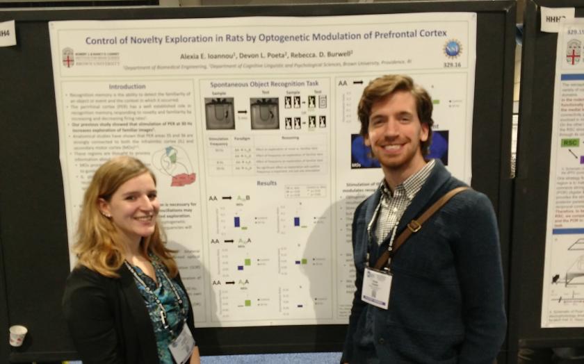 Two students stand in front of their research poster