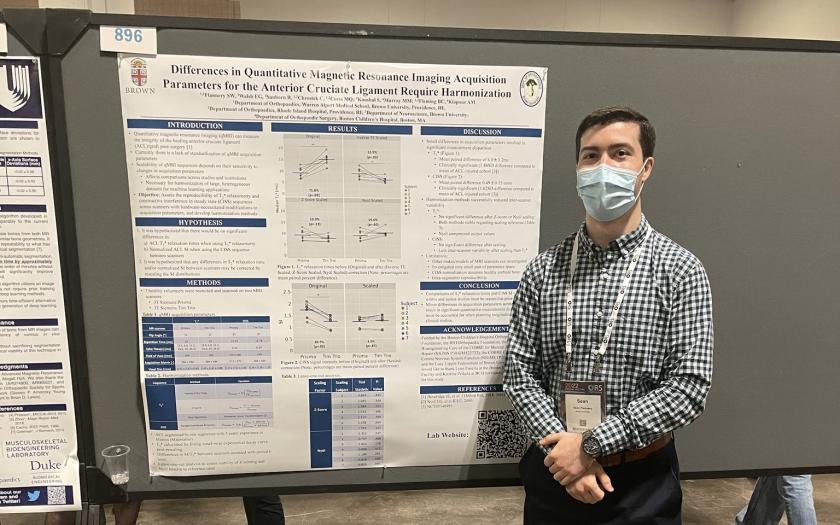Sean Flannery standing next to his poster