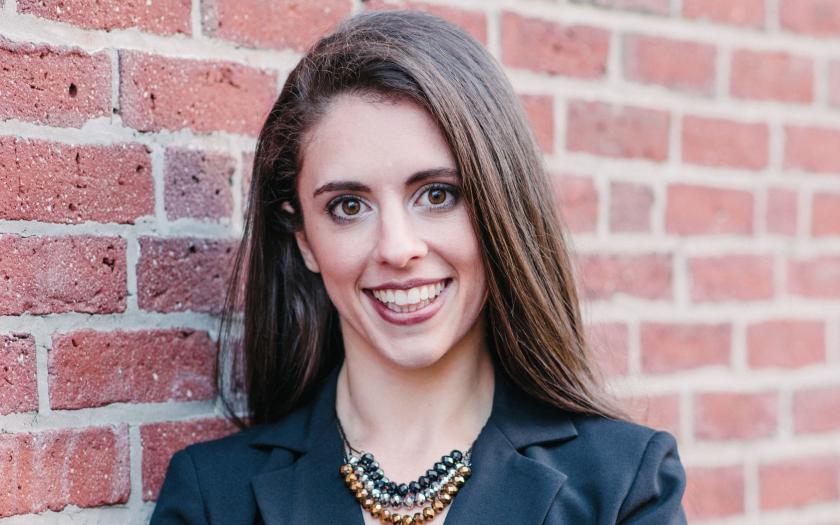 Theresa Raimondo standing against a brick wall