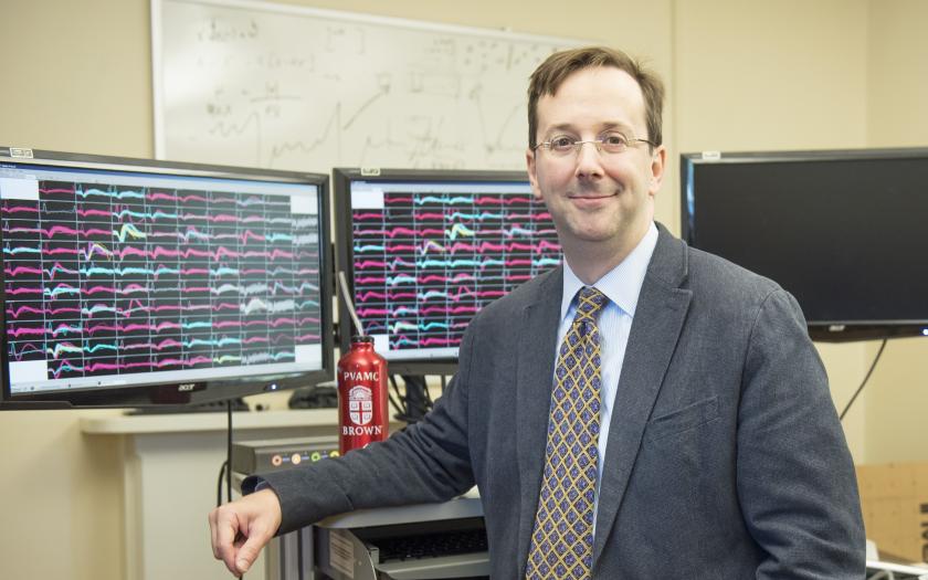 Leigh Hochberg standing in front of computers displaying charts