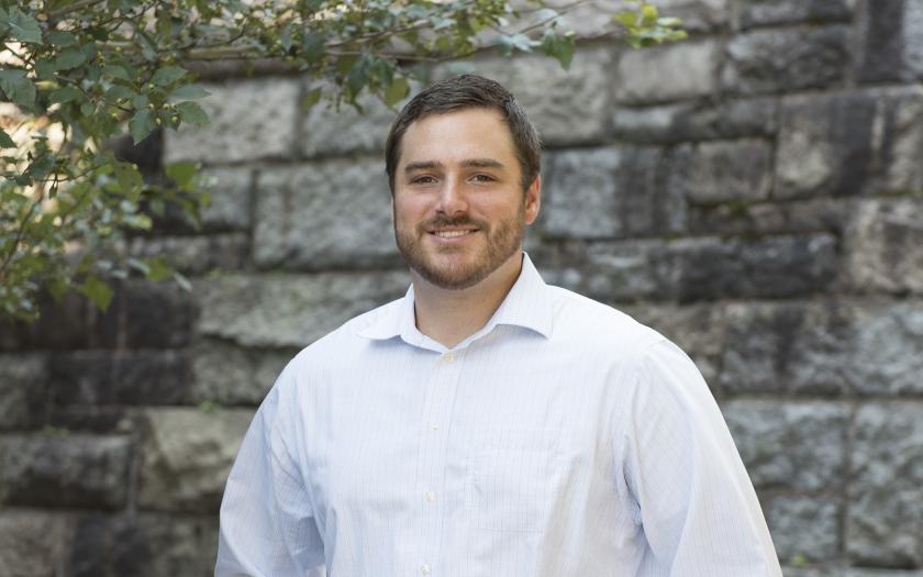 Bryan Sutermaster standing near a tree in front of a wall