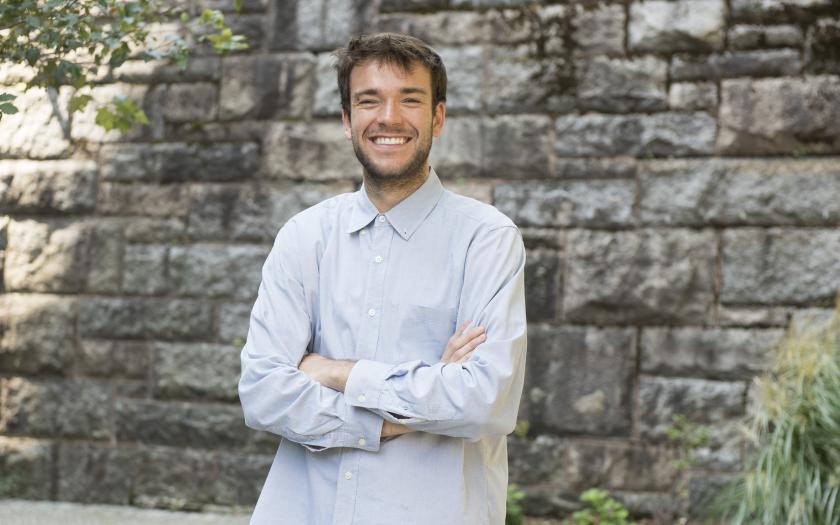 Ben Wilks posing with a smile in front of a stone wall