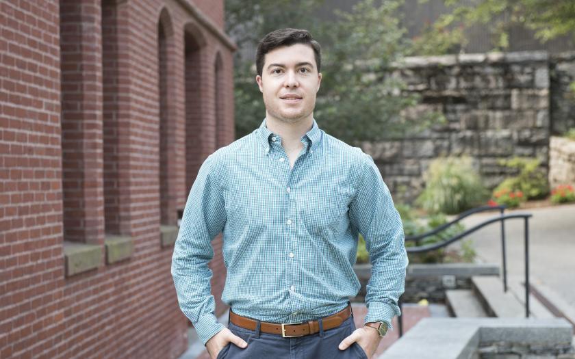 Sean Flannery posing for a portrait next to a brick building