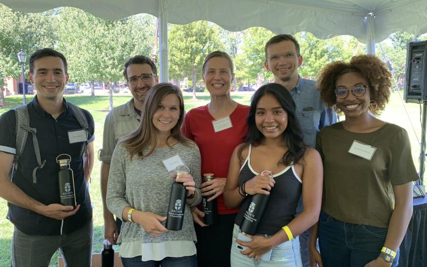Seven students pose with water bottles 
