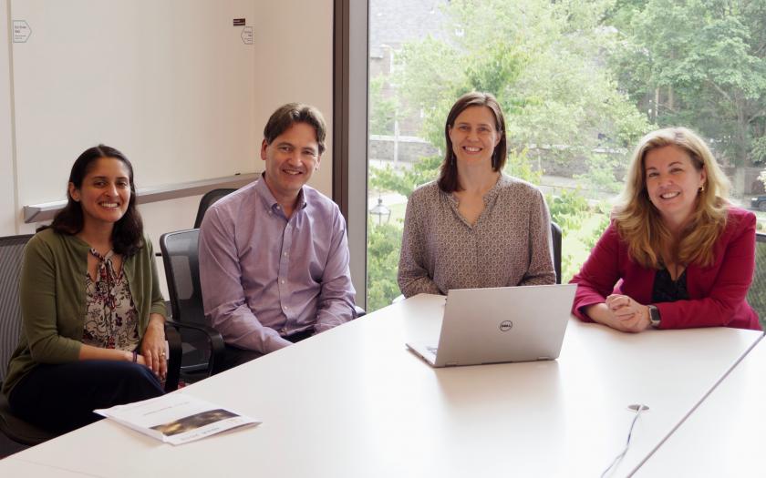 Four people sit around a table smiling